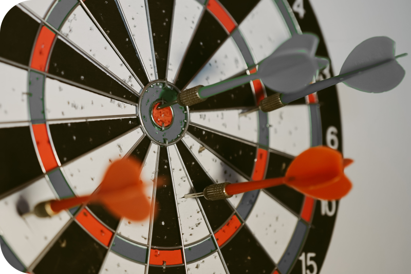 Dartboard stuck with multiple darts representing how a marketing strategy can focus multiple marketing activities in one direction towards a single goal.